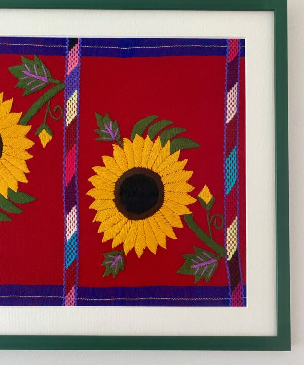 Framed yellow sunflowers detail on a red cloth background with a slim green frame.