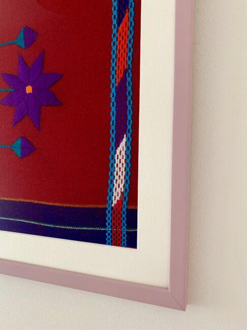 Detail of a pale lilac frame housing a red Mexican embroidery textile.