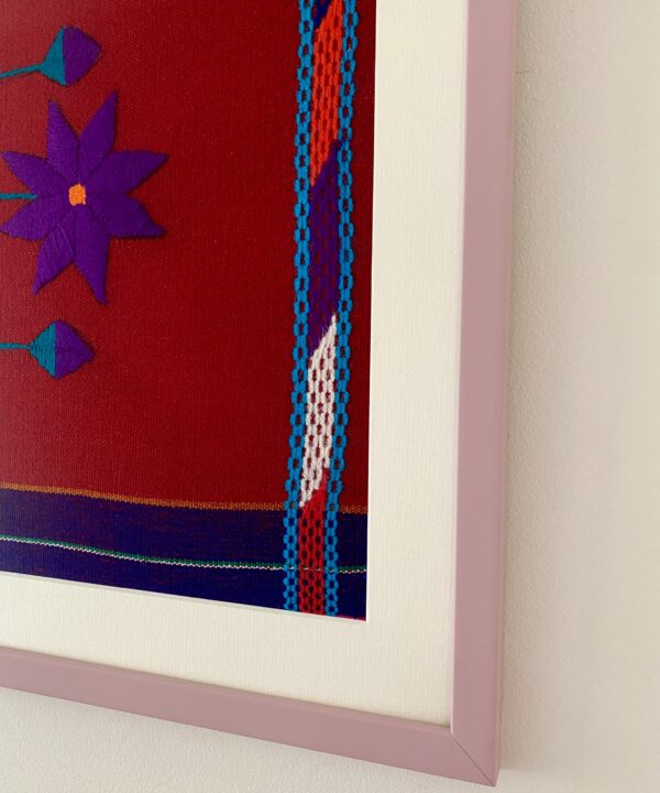 Detail of a pale lilac frame housing a red Mexican embroidery textile.