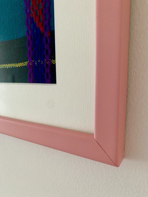 Detail of the corner of a pink framed Mexican textile.