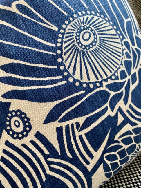 Close-up shot of a Protea print floral fabric on blue floral cushion covers.