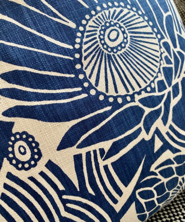 Close-up shot of a Protea print floral fabric on blue floral cushion covers.