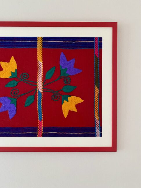 A red, yellow and violet Mexican textile embroidery framed in red.