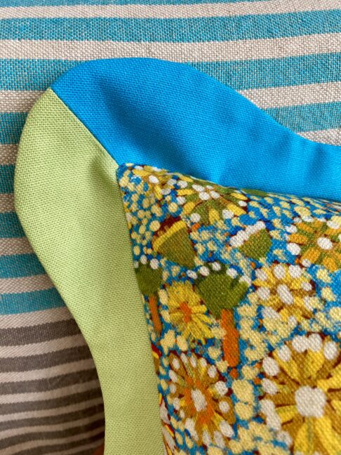 A detail shot of a scalloped edge cushion in blues and green.