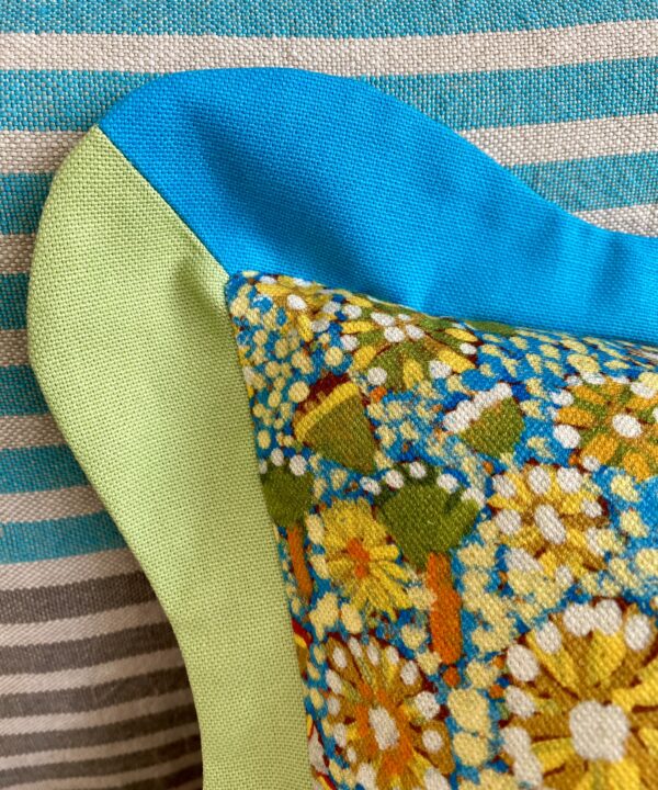 A detail shot of a scalloped edge cushion in blues and green.