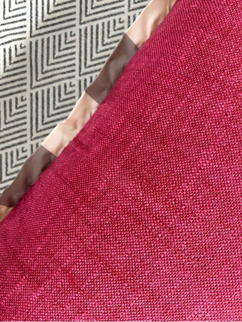 Detail of the red woven fabric reverse of a floral cushion cover with a neutral stripe trim.