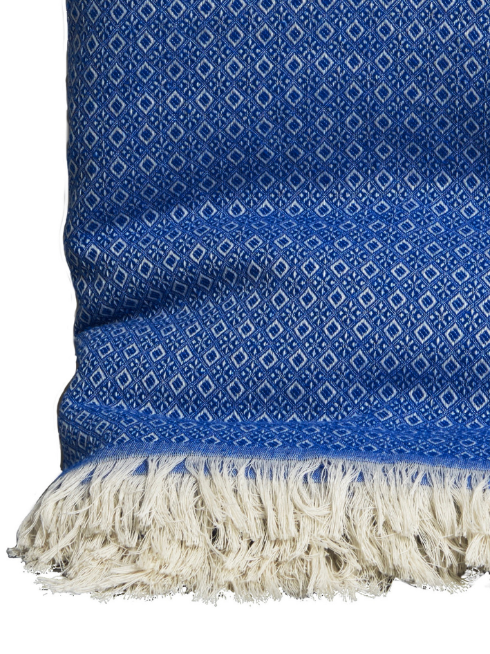 A Royal blue cotton bed throw with cream fringing from The Cotton Poet.