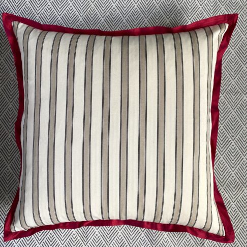 The striped ticking reverse of a large floral print cushion with scarlet silk trim.