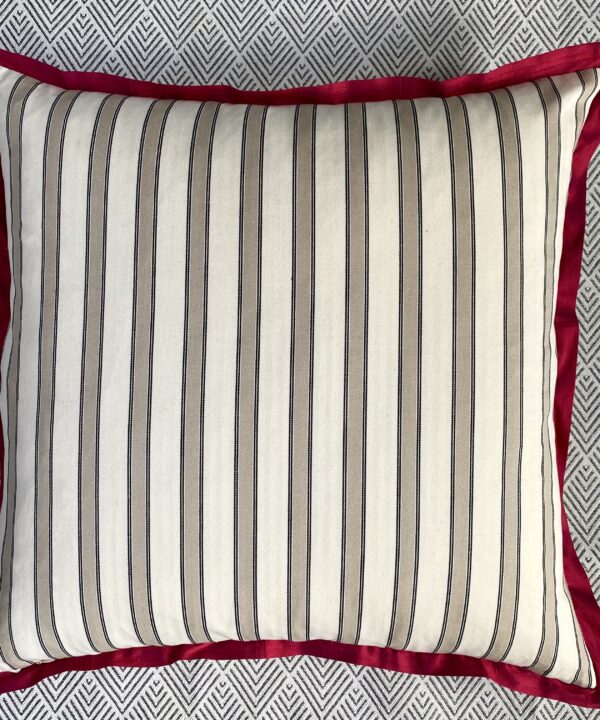 The striped ticking reverse of a large floral print cushion with scarlet silk trim.