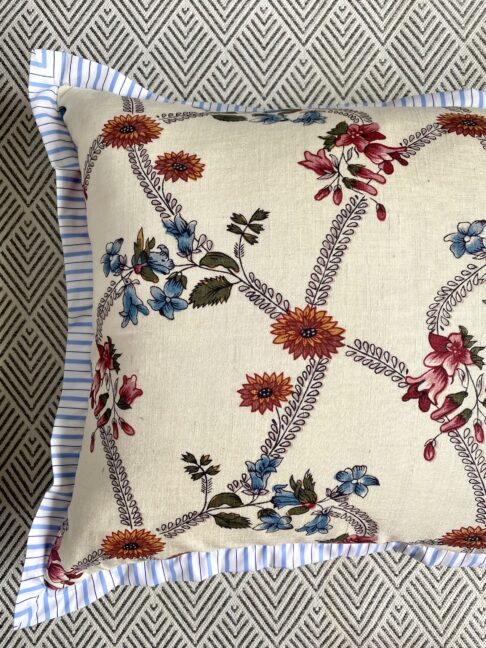 A vintage floral cushion with a blue stripe trim.