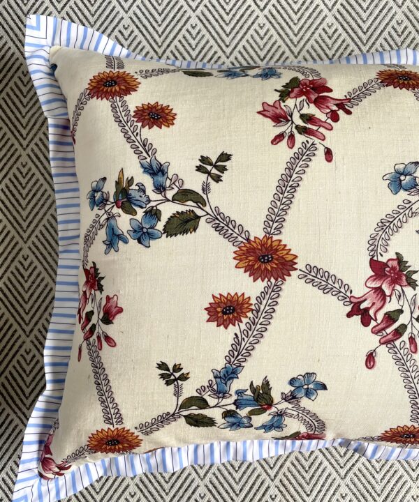 A vintage floral cushion with a blue stripe trim.