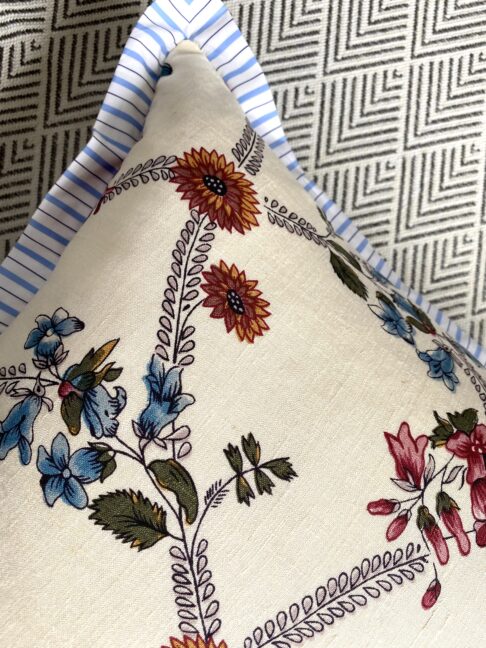 Detail of na pretty floreal sprig cushion with pale blue stripe trim.