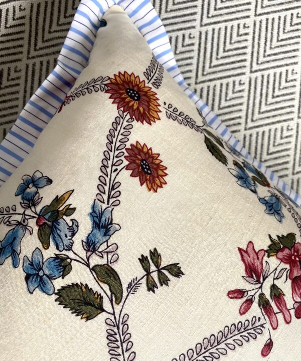 Detail of na pretty floreal sprig cushion with pale blue stripe trim.