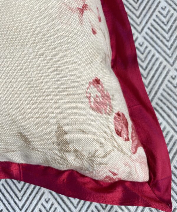 Detail of a vintage rose cushion in linen with deep red silk trim.