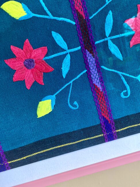 Colourful embroidered flowers with neon accents on a piece of Mexican handicraft textile.