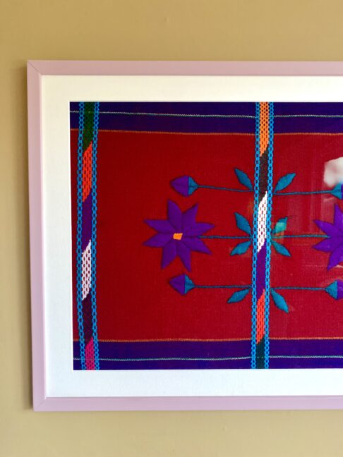 Handmade embroidery art textile from Mexico framed in a lilac frame.