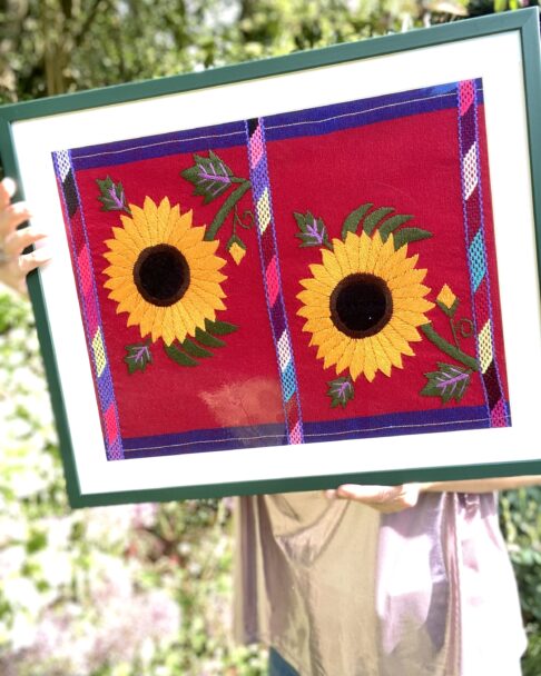 Embroidered sunflowers on a Mexican textile in a green frame.