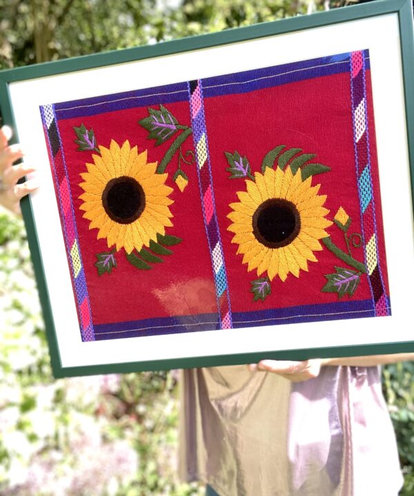 Embroidered sunflowers on a Mexican textile in a green frame.