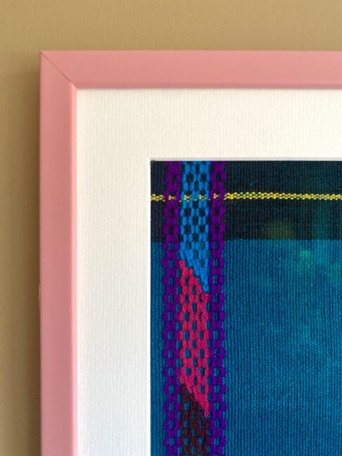 Corner detail of a smart, baby pink frame used for textile wall art.