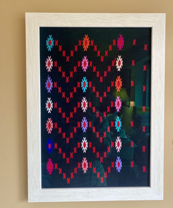 A wall art piece created from brightly coloured embroidered motifs on a black cotton ground.