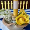 A bloom-filled ceramic candlestick with a stripy yellow and white dinner candle.