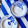 Vintage French bowls set in blue and white with transferware floral detailing shown on a Royal blue and white striped tablecloth.