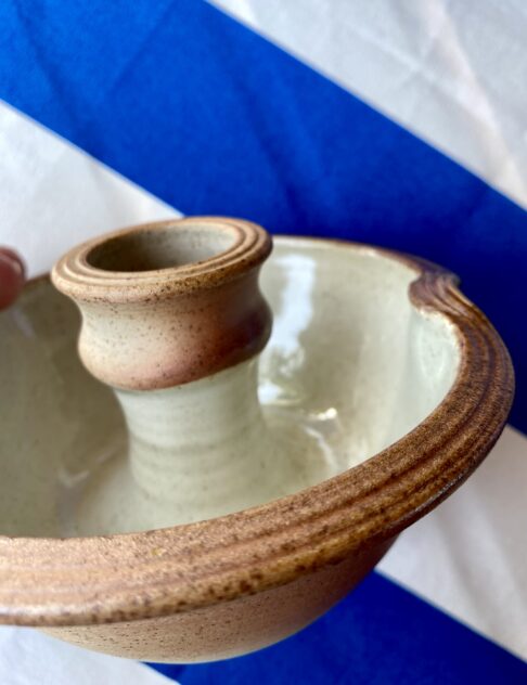 Detail of an ivory-glazed, pottery, ceramic candlestick.