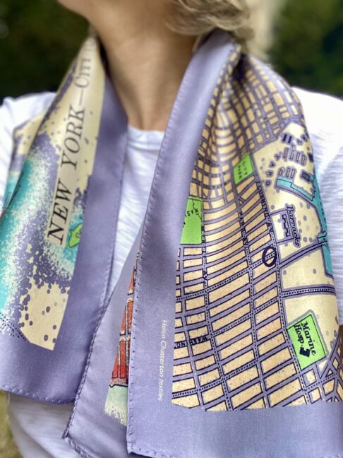 An elegant silk scarf in lilac, turquoise, green and red depicting a vintage map of New York City.