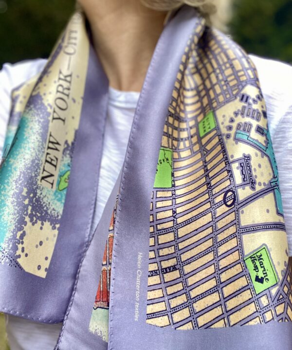 An elegant silk scarf in lilac, turquoise, green and red depicting a vintage map of New York City.