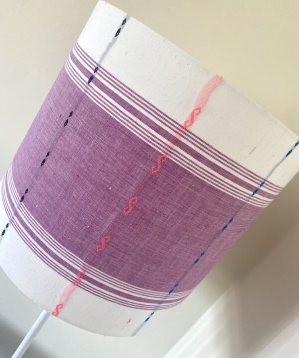 Mauve lampshades with white bands top and bottom and multi0coloured stitched detailing.