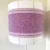 Mauve lampshades with white background and multi-coloured detailing.