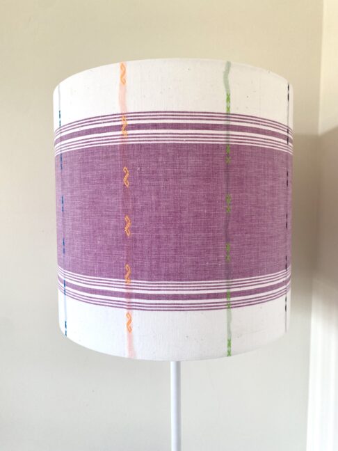 Mauve lampshades with white background and multi-coloured detailing.