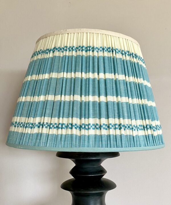 Pale blue gathered lampshades in hand-loomed cotton with a horizontal striped design.