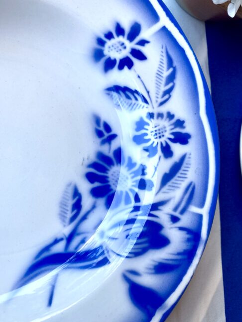 Close up detail of French transferware floral on a ceramic dish in blue and white.