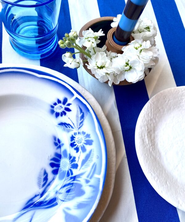 Royal blue and white place setting with striped tablecloth and vintage French blue and white bowls.