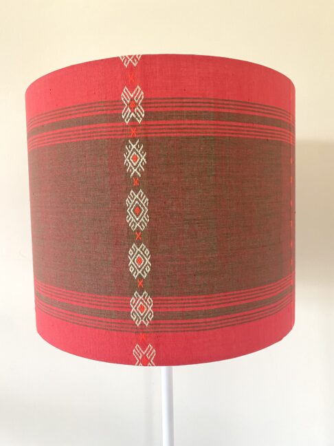 Colourful red lampshades handmade from South East Asian cotton in a drum shape.