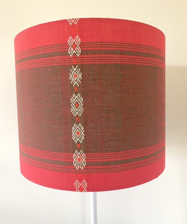 Colourful red lampshades handmade from South East Asian cotton in a drum shape.