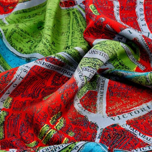 Close up image of a luxury silk scarf with a vintage London map print in red.