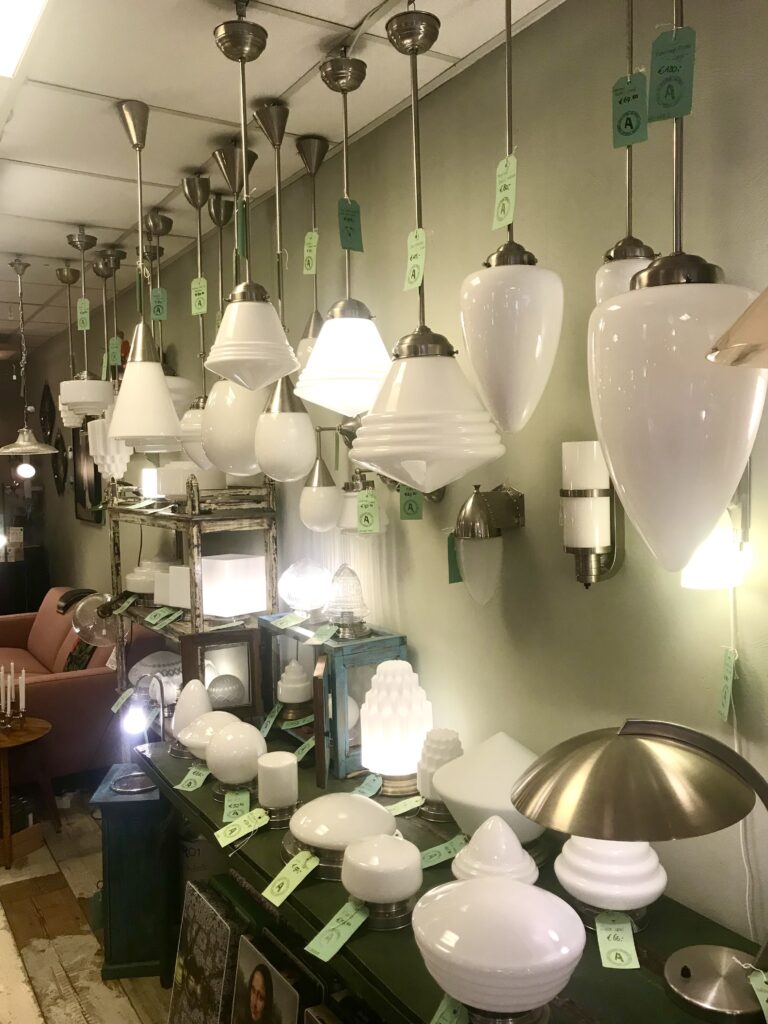 A selection of utility-style, vintage milk glass lighting on display in a shop.