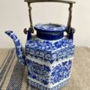 A decorative blue and white hand-painted Thai pottery teapot with lid and metal handle.