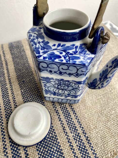 Teapot and lid with decorative blue and white hand-painted lotus flower designs, typical in Thailand.