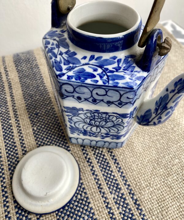 Teapot and lid with decorative blue and white hand-painted lotus flower designs, typical in Thailand.