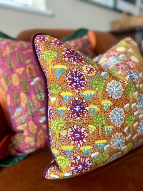 Orange lumbar cushion with floral, indigenous Aboriginal art on linen design.
