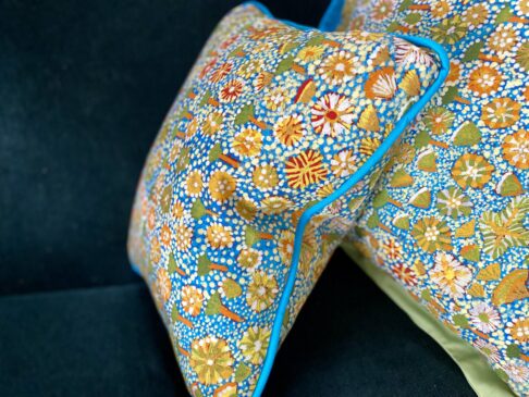 Small rectangular floral print cushion with Aboriginal art botanical print in turquoise, green and yellow.