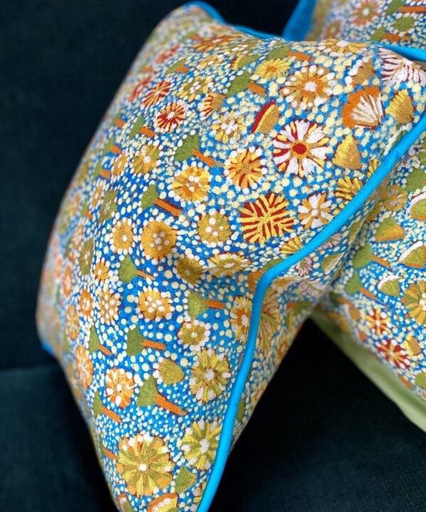 Small rectangular floral print cushion with Aboriginal art botanical print in turquoise, green and yellow.