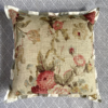 A vintage faded floral cushion cover with a red woven reverse and neutral stripe silk trim.