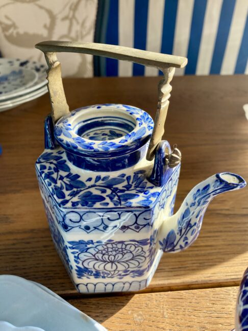 A vintage Thai tea pot with blue and white lotus flower decoration and metal handle.