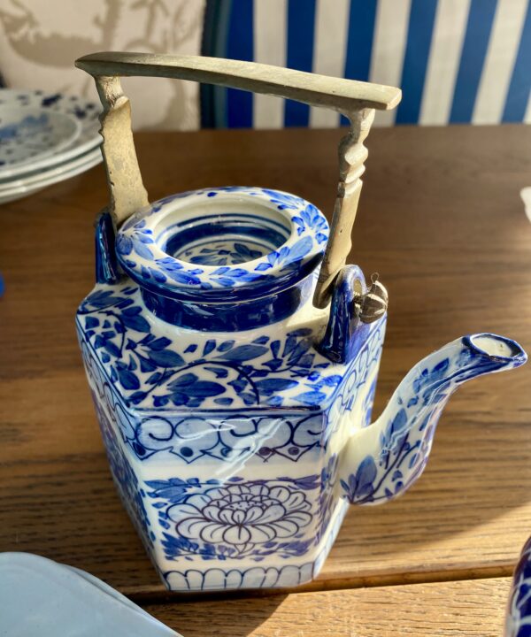 A vintage Thai tea pot with blue and white lotus flower decoration and metal handle.