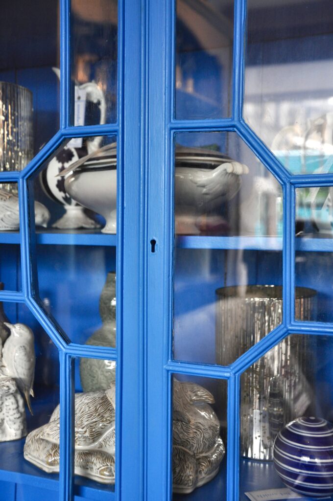 Astragal glazing on a blue-painted cabinet filled with china.