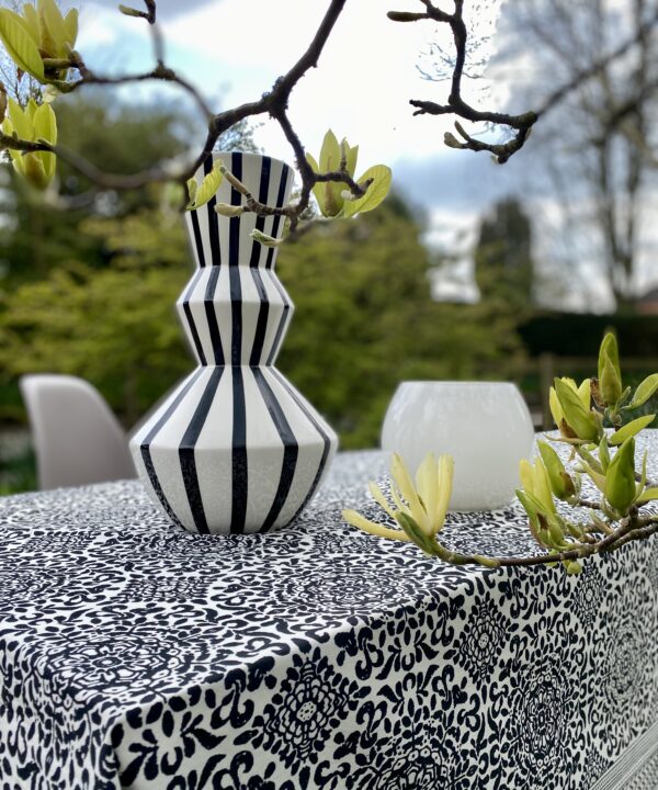 A monochrome tablescape with a stripy vase and magnolias in the foreground.